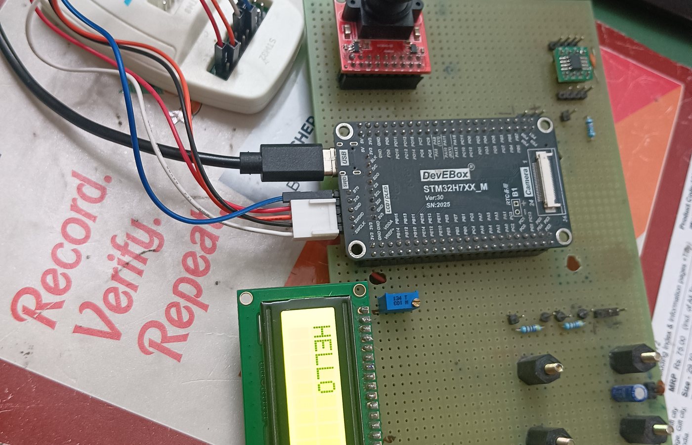 STM32H7 development board with LCD displaying HELLO and camera module on a prototype board